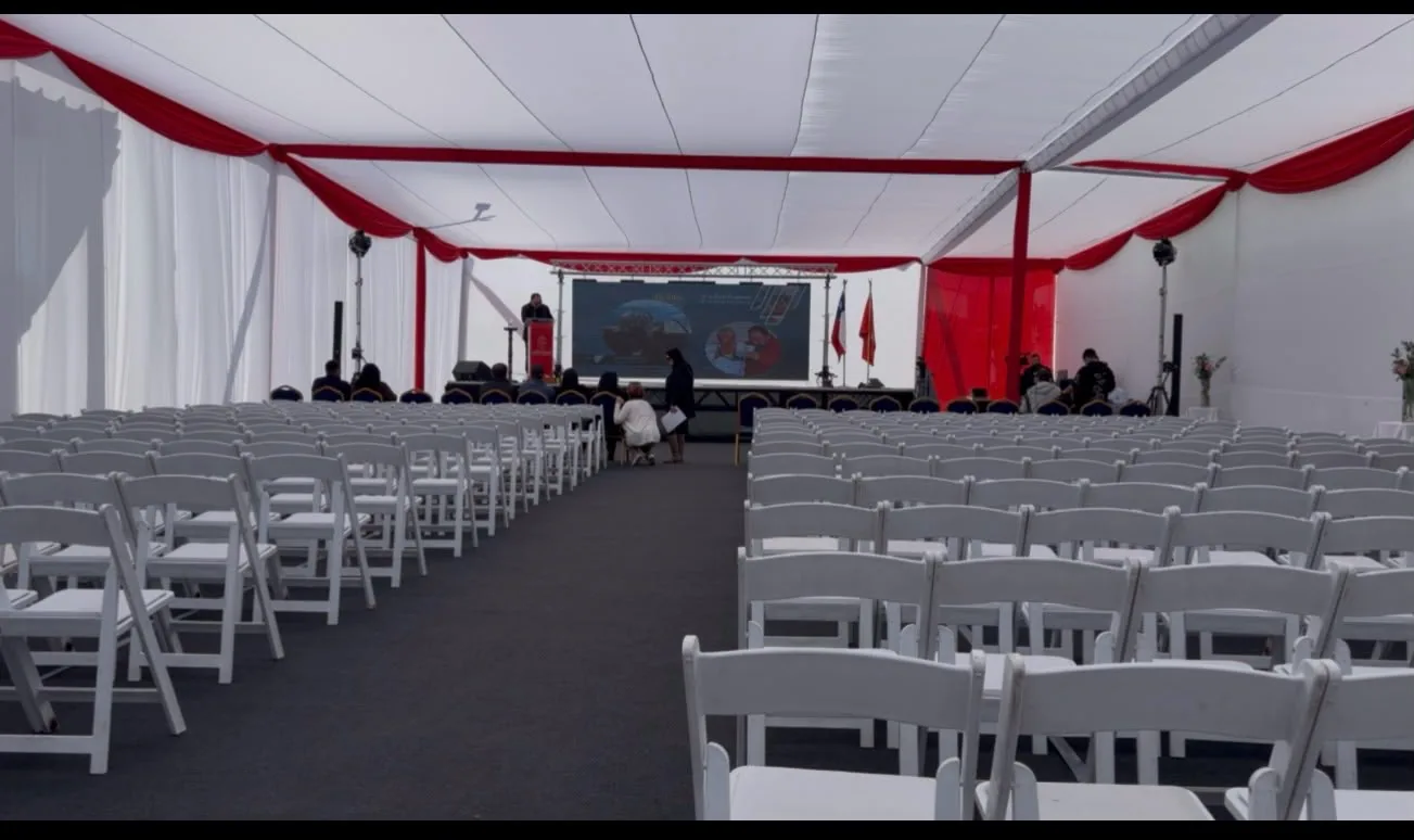 Carpa corporativa con sillas, escenario y pantalla